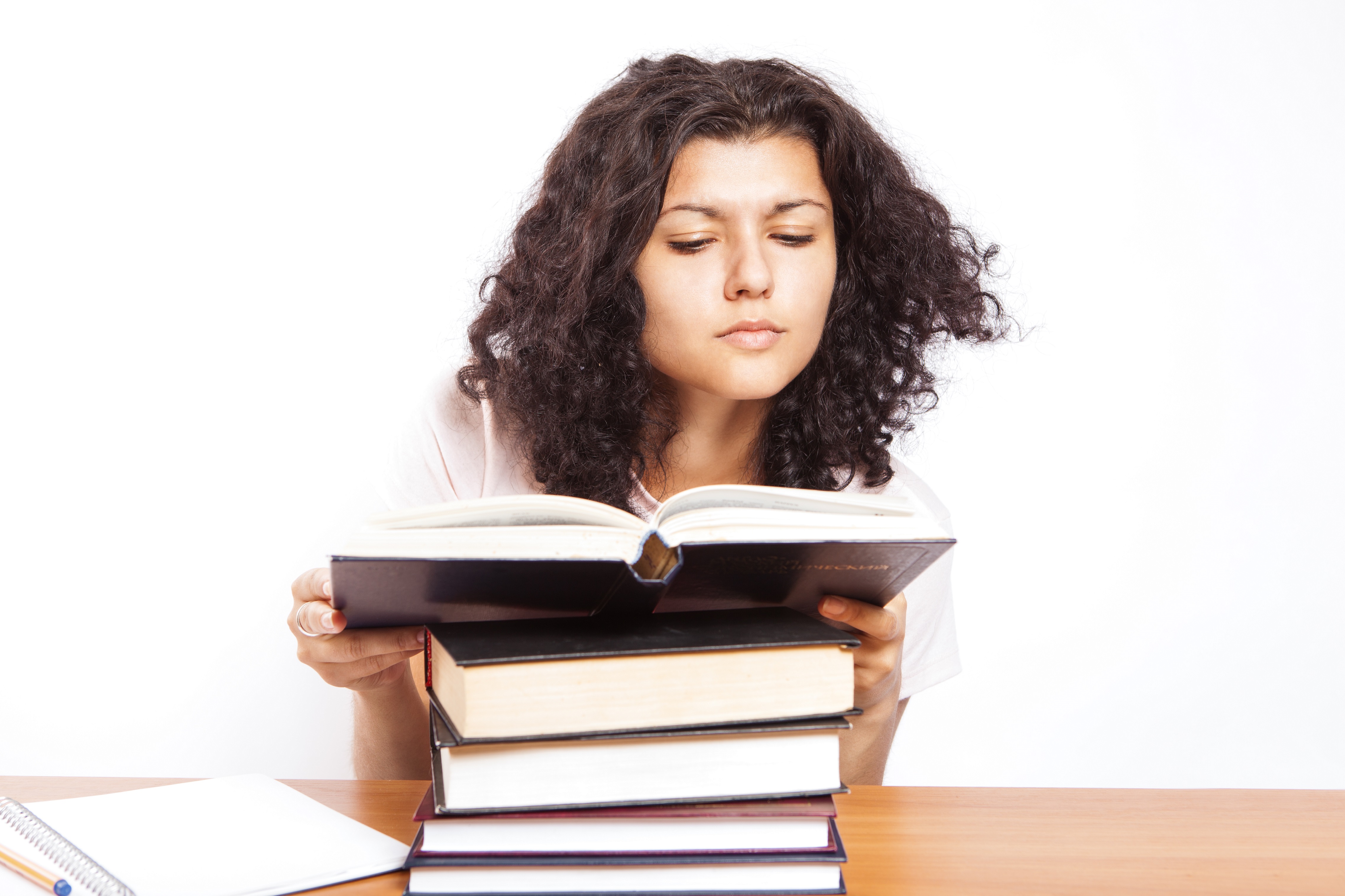 Girl with a stack of books reading inquisitively